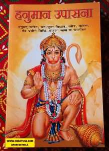 'Hanuman Upasana' in Hindi, featuring a vibrant illustration of Lord Hanuman kneeling with a mace, set against an orange background."