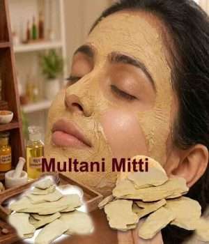 A woman applying a thick, creamy grey-brown paste of Multani mitti face pack