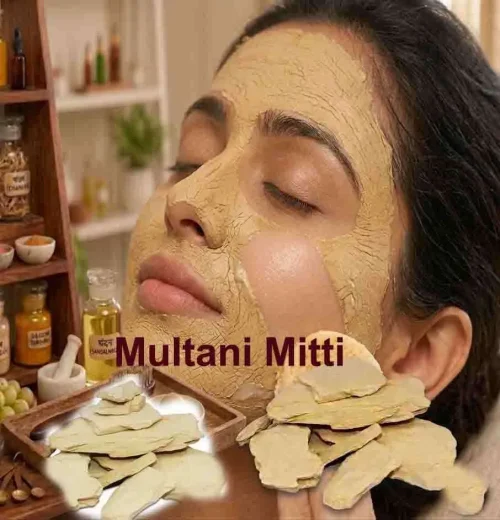 A woman applying a thick, creamy grey-brown paste of Multani mitti face pack
