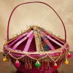 Handmade-woven bamboo basket (known as a Phuldali or Saji). Red colored basket is a staple of Mithila culture in Bihar, India, and is primarily used to carry flowers for religious rituals. The basket features a conical, ventilated lid adorned with gold tinsel, colorful embroidery, and hanging decorative tassels with small metallic bells, topped with a tall, curved handle for easy carrying. todayuse or apan mithila
